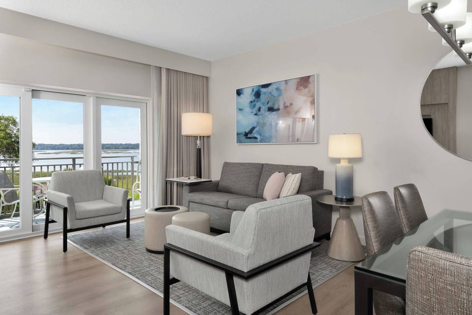 Living room features a sleeper sofa, TV, and door to the balcony (view varies-assigned at check-in)