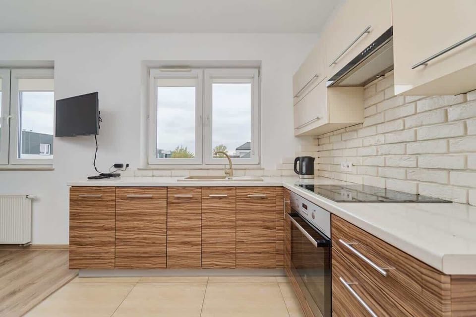 A detailed view of the kitchen, featuring wooden cabinetry, a modern oven, and clean white countertops with a tiled backsplash.
