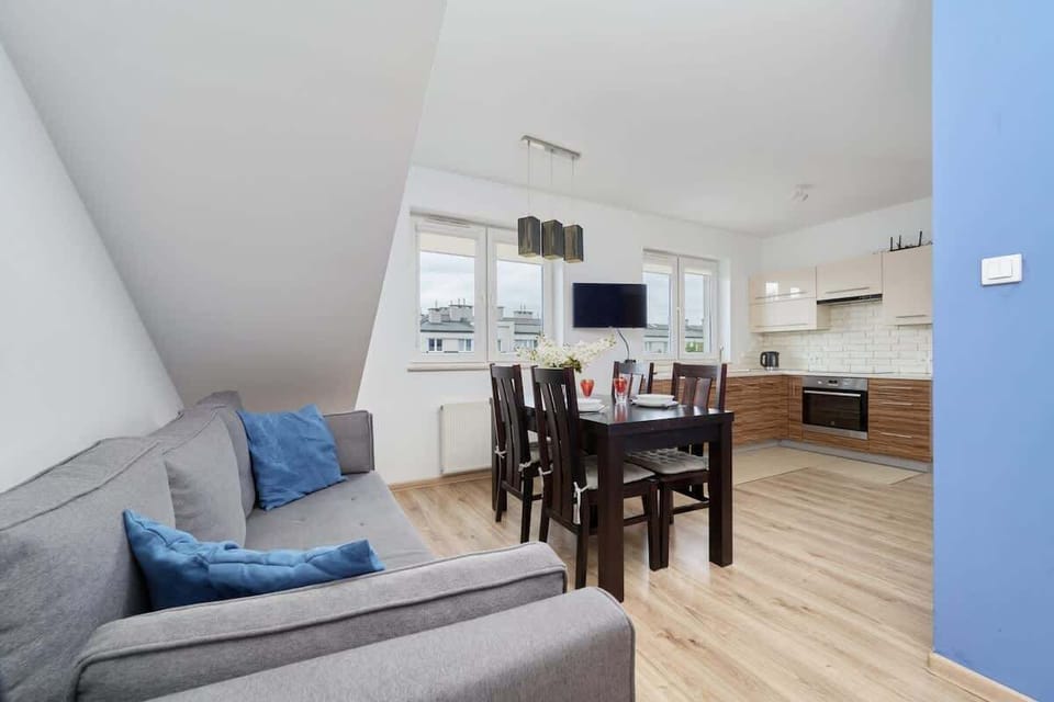 A combined living and dining area with a grey sofa, a dining table, and plenty of natural light, creating an open and welcoming atmosphere.
