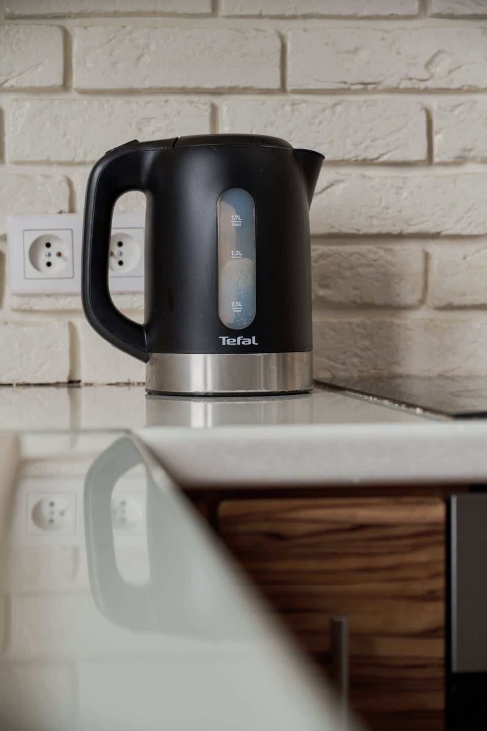A close-up of the kitchen counter, showcasing a black electric kettle against a light tiled backsplash, blending functionality with style.
