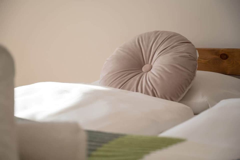 A bedroom with a double bed featuring green and white bedding, a bedside table, and a wardrobe, creating a warm atmosphere.
