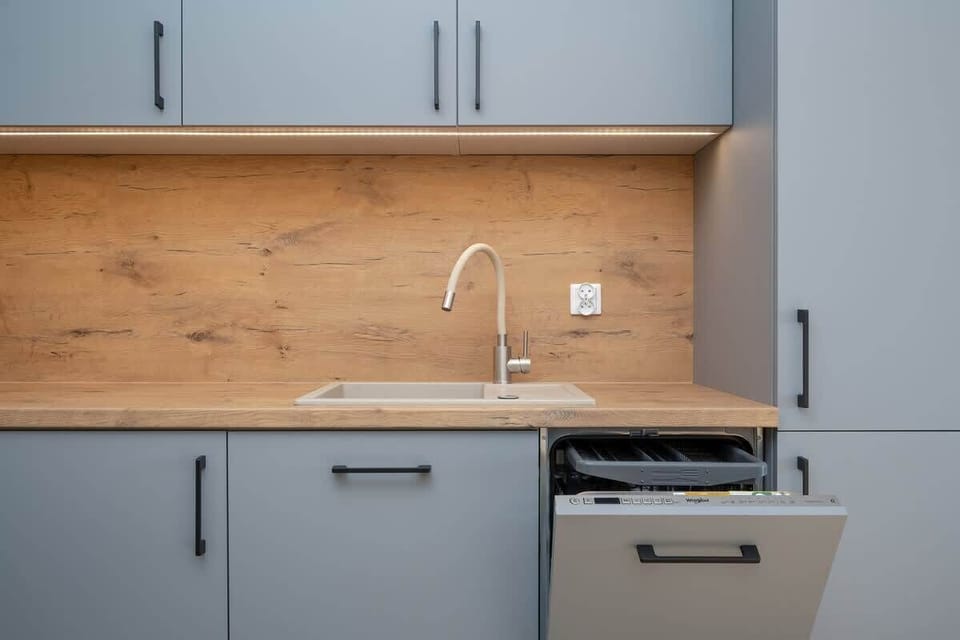 A modern kitchen with grey cabinets, a wooden backsplash, and sleek appliances, designed for functionality and style.
