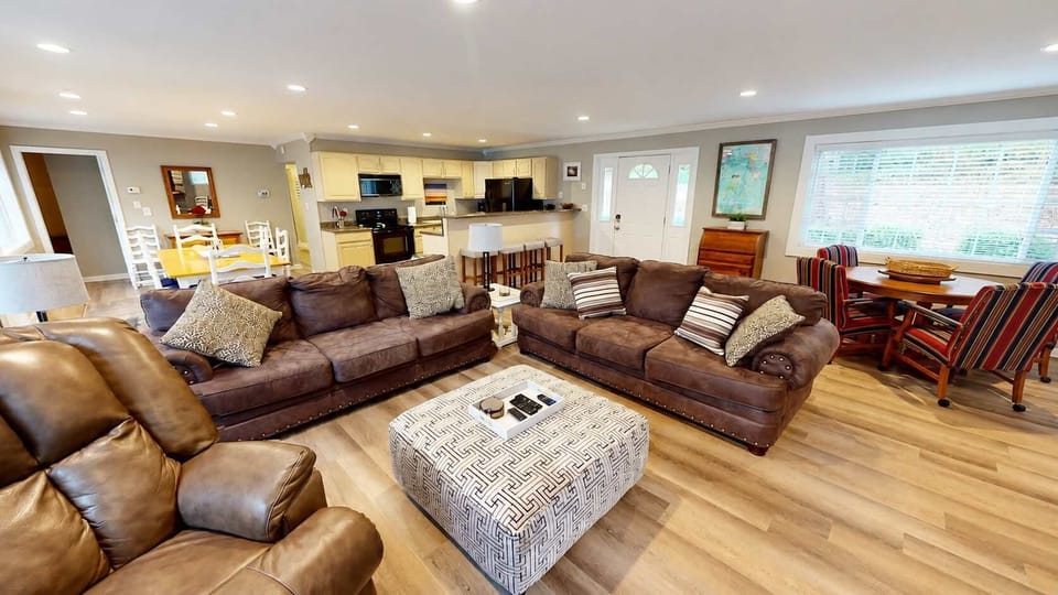 Relax and unwind in this spacious living room with brown sofas and an armchair.