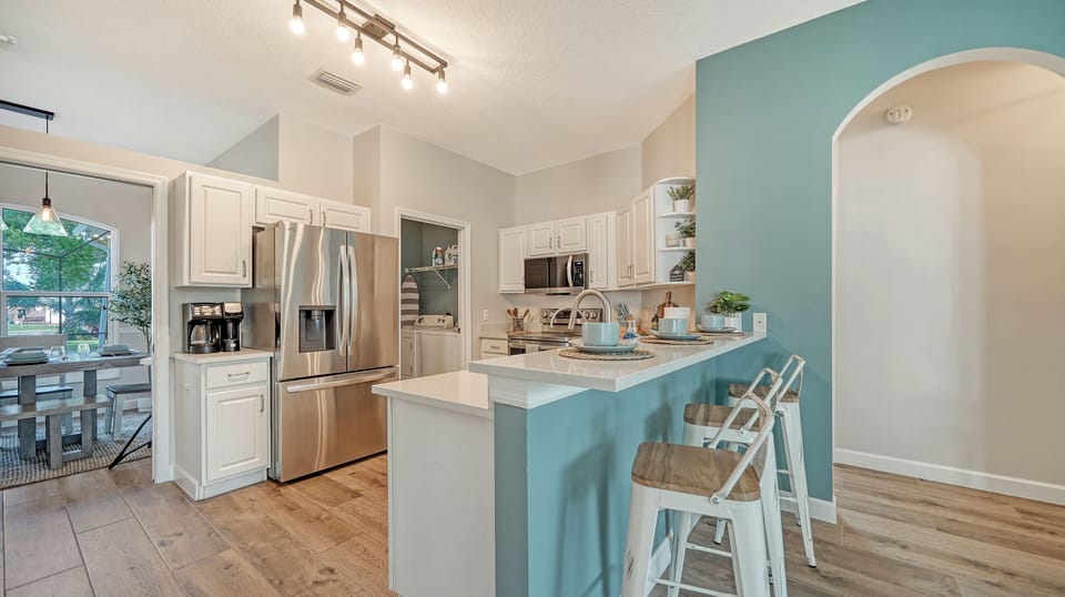 Bright open kitchen, fully stocked, with bar seating for simple family time.
