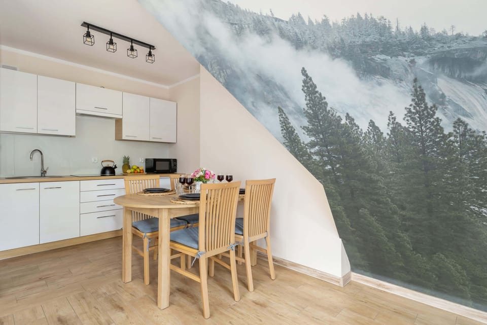 A kitchen and dining area with wooden furniture and a forest mural, creating a harmonious connection to the outdoor scenery.
