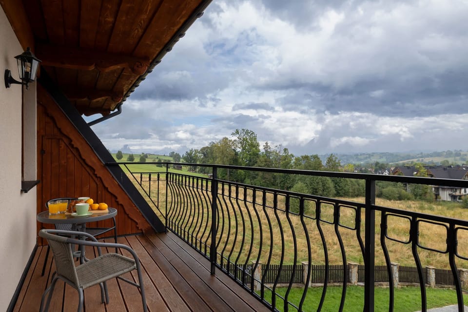 Another perspective of the wooden balcony, emphasizing the spacious layout and beautiful countryside surroundings.
