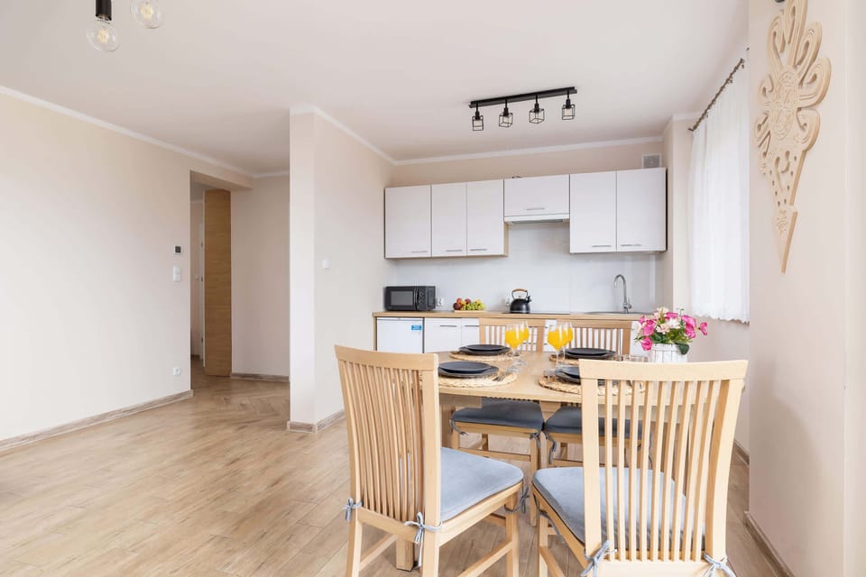 A compact kitchen with a dining table set for four, showcasing sleek cabinetry and a clean design.
