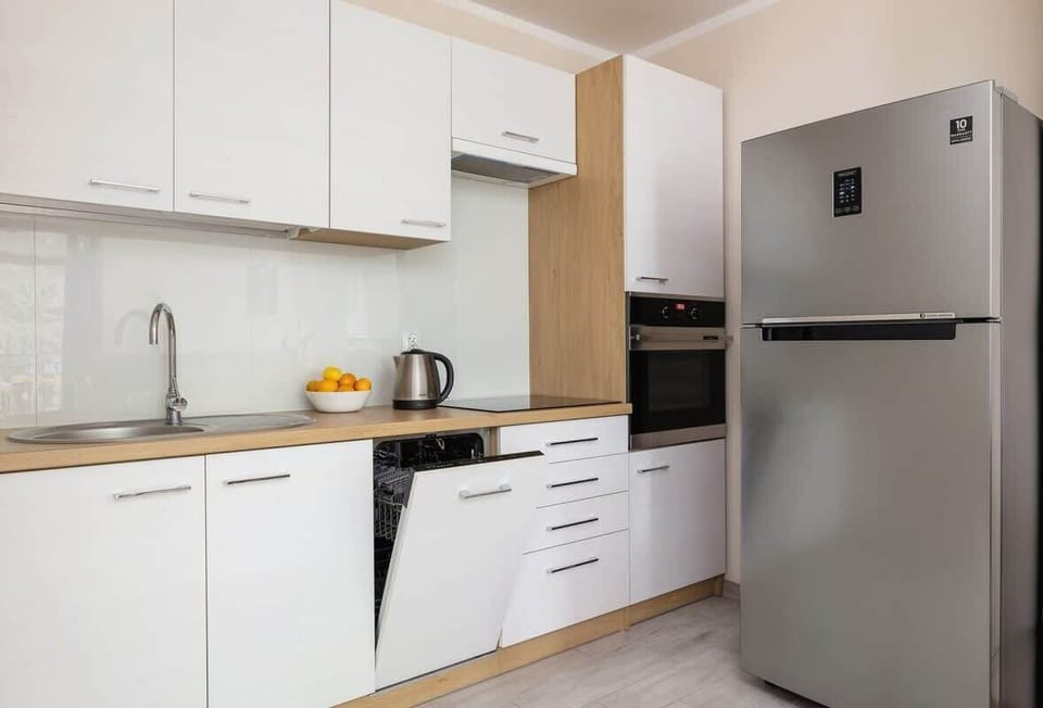 A modern kitchenette with white cabinets, a fridge, and a stovetop, fully equipped for cooking.