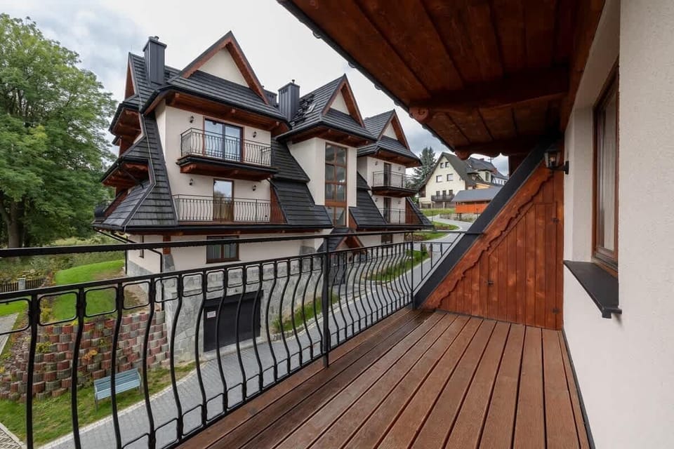 A wooden balcony showing close-up details of the railings and surrounding greenery.