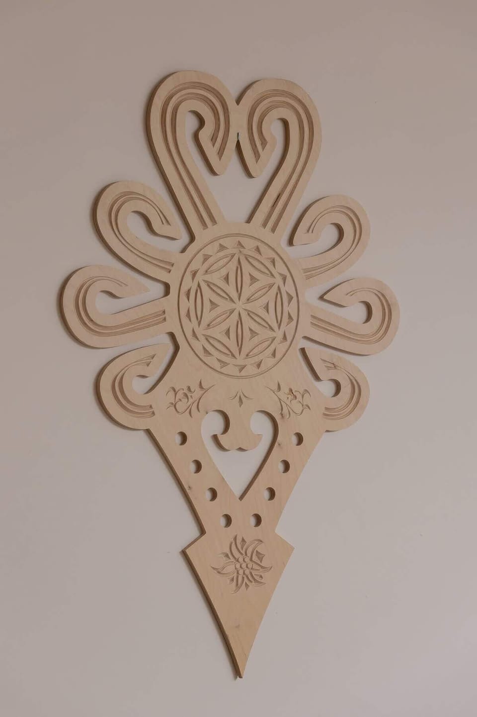 An artistic wall decoration resembling a sconce or decorative piece in beige.