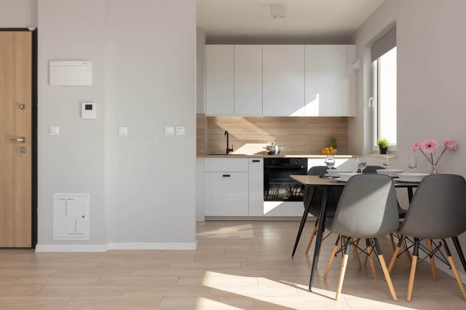 A compact yet functional kitchen and dining area with pastel accents and elegant furniture.
