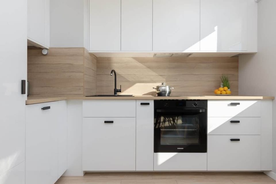 A modern kitchen with white cabinets, a wooden countertop, and a built-in oven, combining practicality with style.
