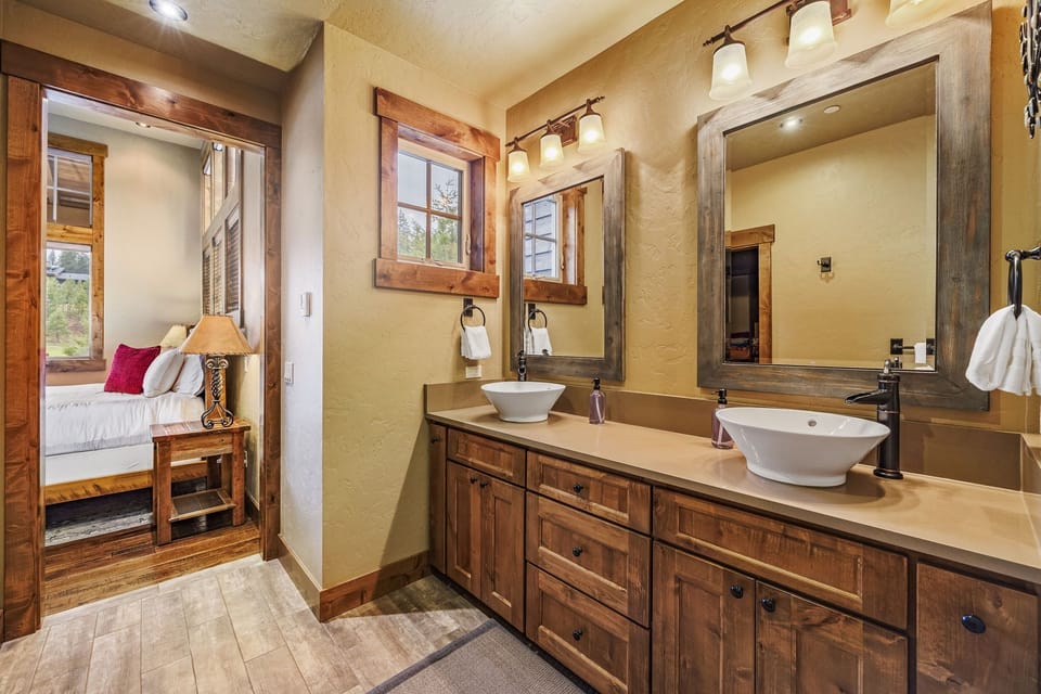 Experience the pinnacle of relaxation in the en suite of this mountain sanctuary, boasting a heated tile floors, and two modern vessel-mounted sinks