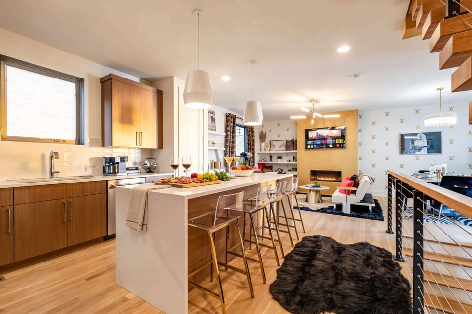 Open kitchen, island seating, and a fireplace anchoring the living room mean the group stays together all day and night