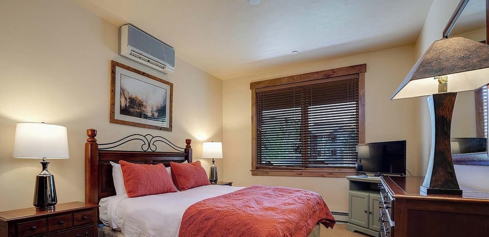 Sink into comfort in your elegantly appointed bedroom, where rich wood furnishings and warm coral accents create the perfect retreat for restful nights.