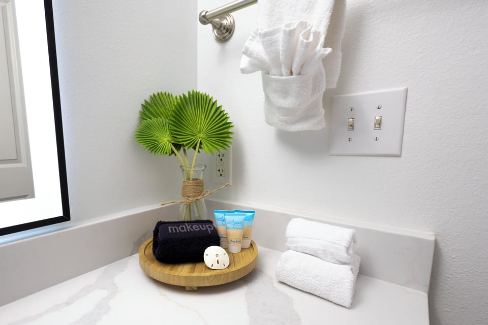 Modern bathroom countertop with neatly arranged toiletries and fresh towels.
