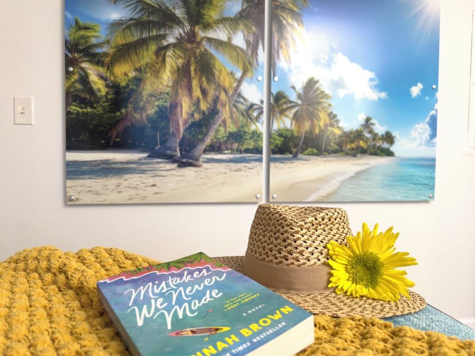 A cozy reading nook with a tropical beach wall art and a sun hat for a relaxing escape.