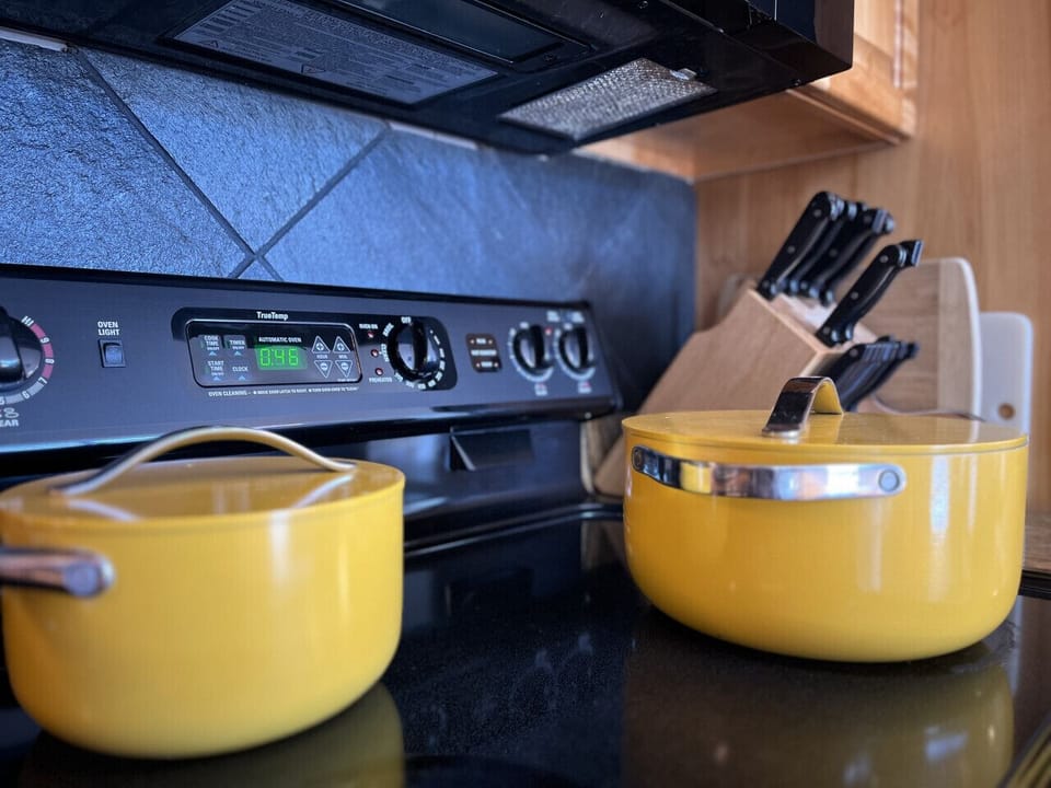 Sleek stove setup with vibrant yellow pots and utensils