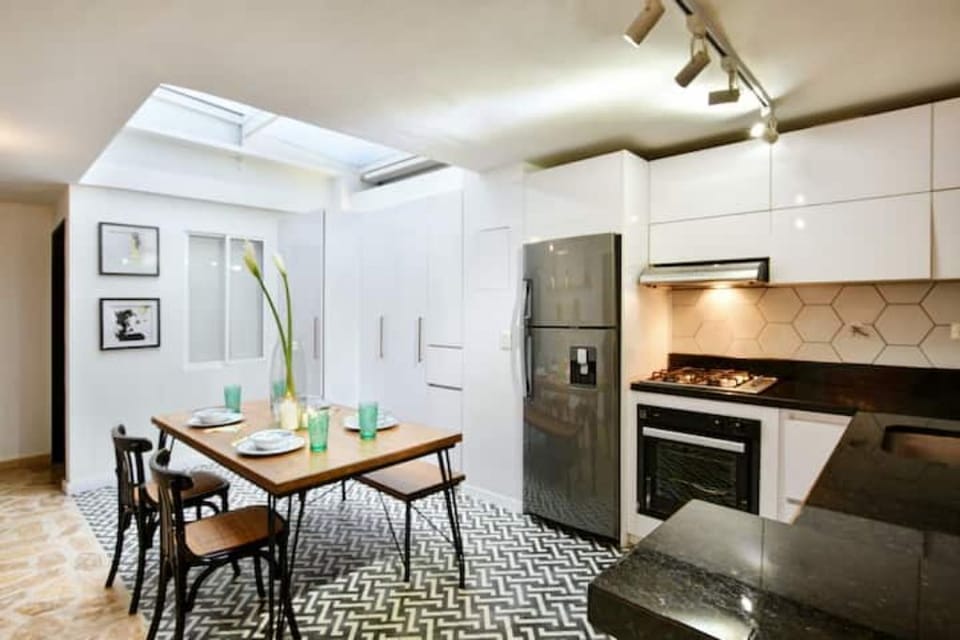 Four-person dining table which sits under opaque skylight.