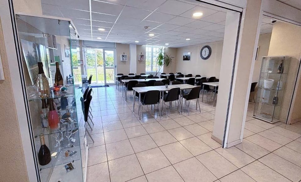 Gather for meals or events in this spacious room, illuminated by natural light filtering through large windows.