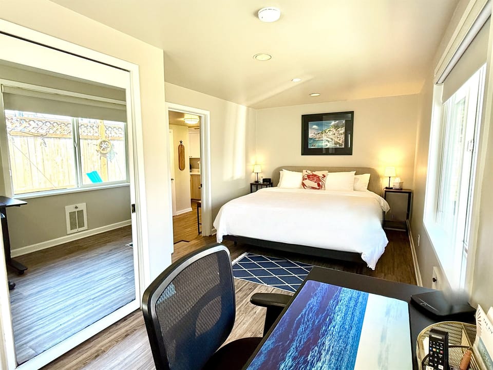 Spacious king bedroom with soft linens, desk, and natural light—guests love this bed!