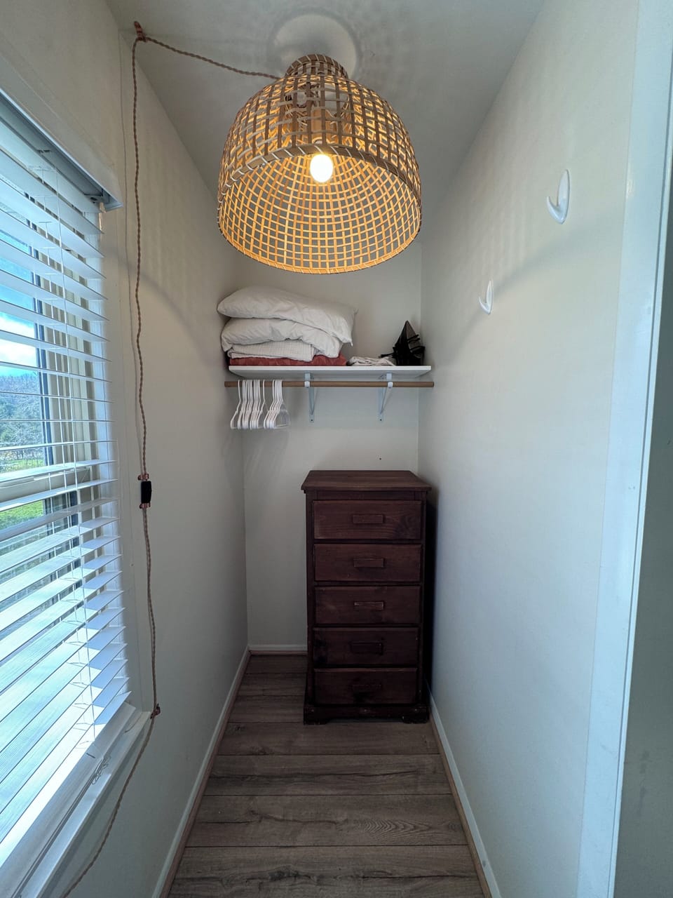 Primary bedroom closet w/ extra linens, clothing storage, iron/ironing board