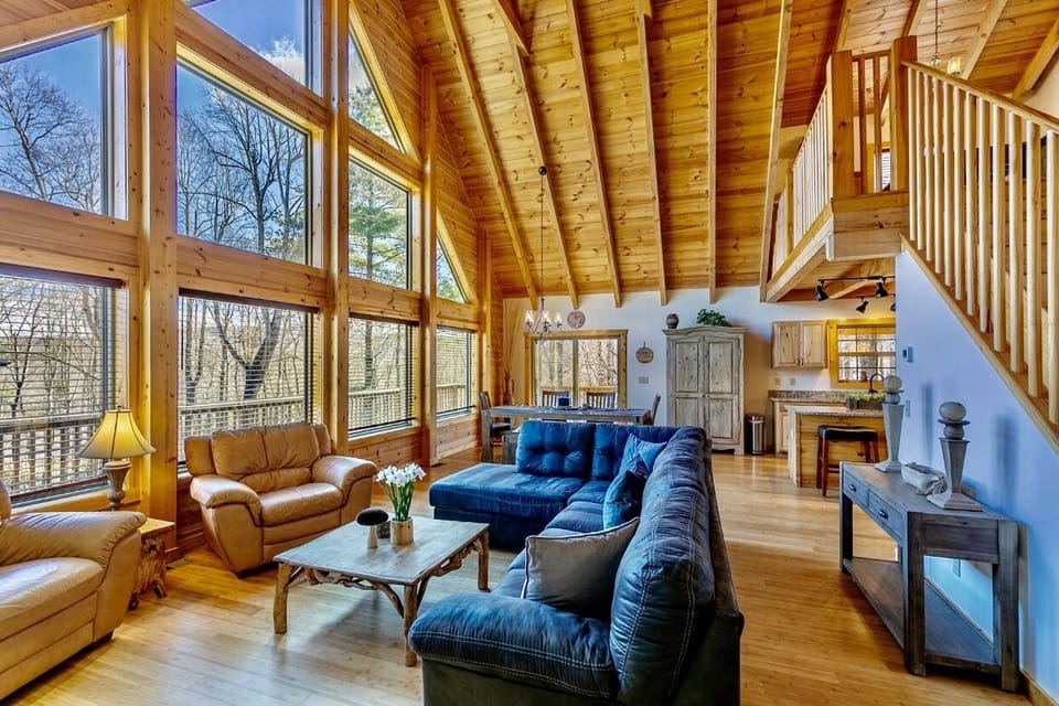 Open concept Living room with bamboo flooring, wooden A-framed ceiling, huge windows comfortable couches and arm chairs