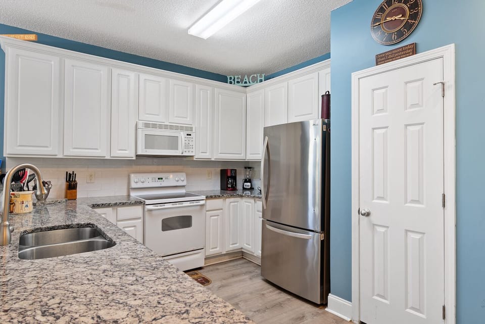 Your fully equipped kitchen with granite counters, stainless appliances, and beachy blue walls makes meal prep a breeze.