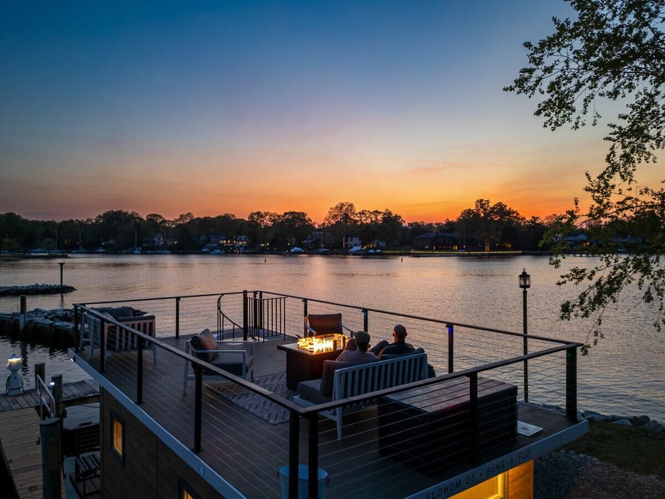 Rooftop fire pit lounge at sunset on the Magothy River, with guests watching the sky go golden over the wooded shoreline at Ferry Point Marina.