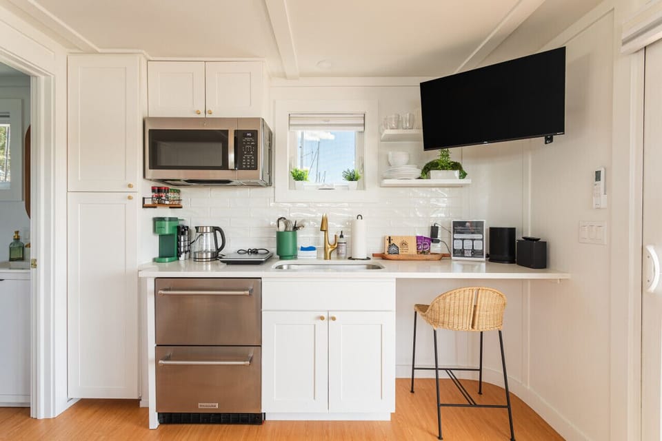 Kitchen with a Keurig coffee maker, KitchenAid drawer fridge, electric hot plate, single-seat bar workstation, and complimentary welcome amenities.