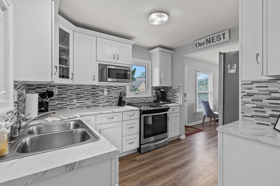 Bright kitchen with white cabinetry, gas range, farmhouse-style sink, and an open view toward the dining nook.
