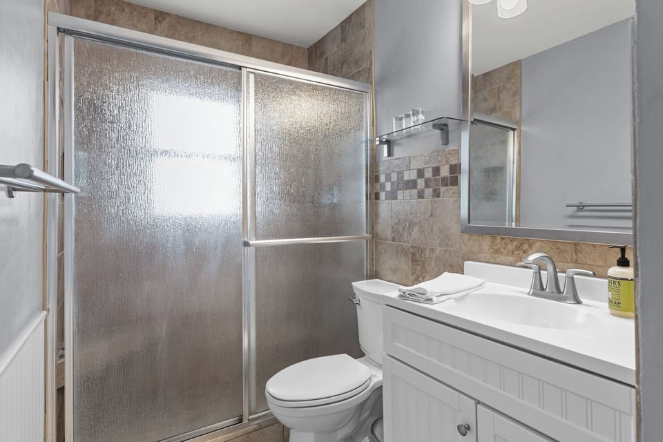 Full bathroom with a glass-enclosed walk-in shower, vanity, toilet, and fresh towels.