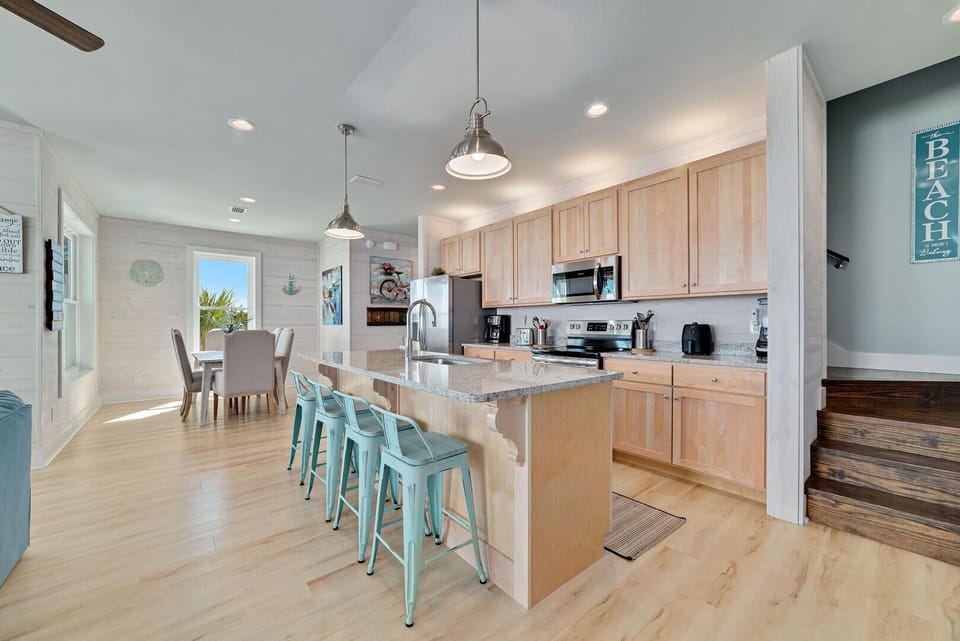 The kitchen boasts a sleek counter bar complemented by four high-top chairs, offering a chic and casual dining spot perfect for quick meals, snacks, or chatting with the chef while cooking.