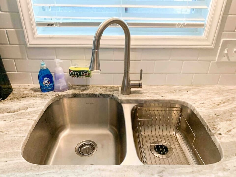 Double sink with fresh sponge, hand soap, dish soap, and drying rack.