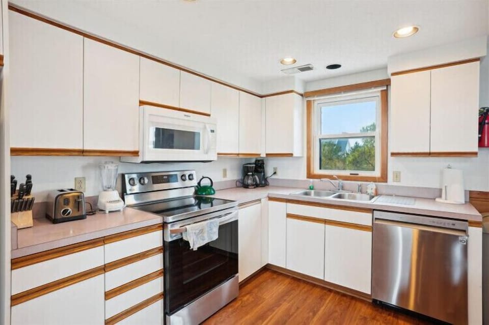 Your fully equipped kitchen awaits, ready for meal prep with modern appliances, ample counter space, and a sunny window framing peaceful natural views while you cook.