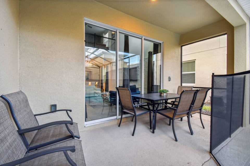 Step outside to this cozy patio, featuring a sleek metal dining set surrounded by comfortable seating. Large sliding doors invite natural light, making this outdoor space ideal for leisurely meals or quiet moments.