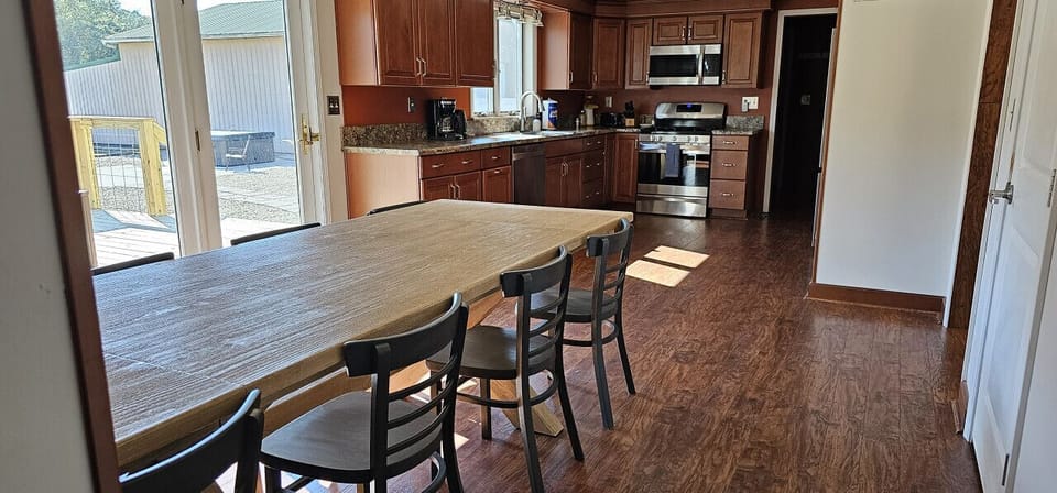 Gather around the large dining table, perfect for family meals or game nights. The nearby shelf is stocked with beach towels and books, making it easy to transition from breakfast to outdoor fun at The Copper House!