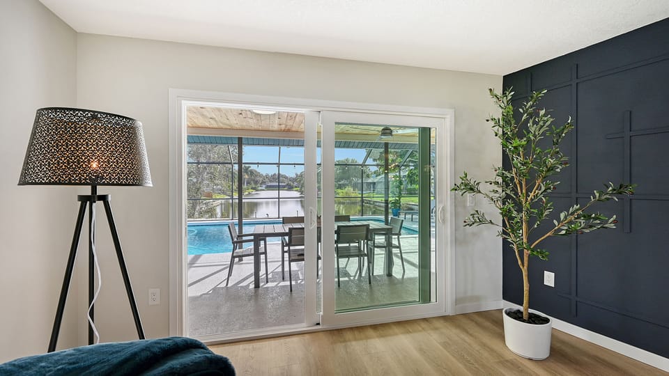 Living room with sectional sofa, standing lamp, and sliding glass door to pool area