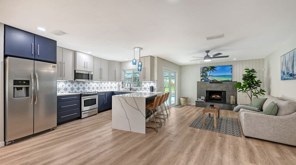 Kitchen with dark navy cabinetry, stainless steel appliances, and decorative tile backsplash