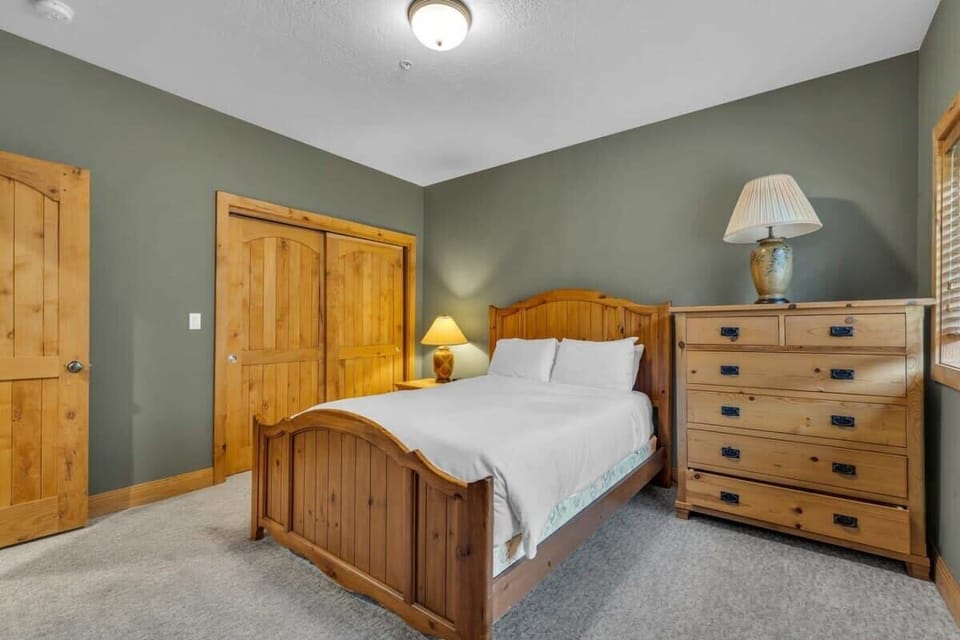 A fourth bedroom is situated on the lower level of the home providing a quiet space outfitted with a queen-size bed, bedside lamps, and a nightstand, dresser, and closet for storage space.