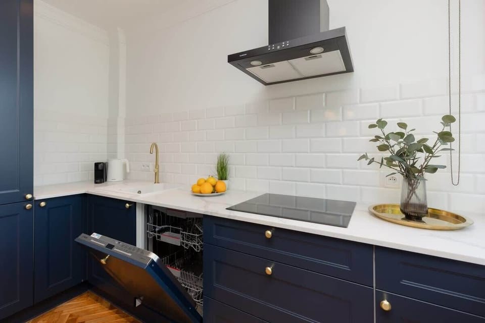 A kitchen shot focusing on the countertop, with a white backsplash and a potted plant adding a touch of greenery. It also features dark blue lower cabinets.