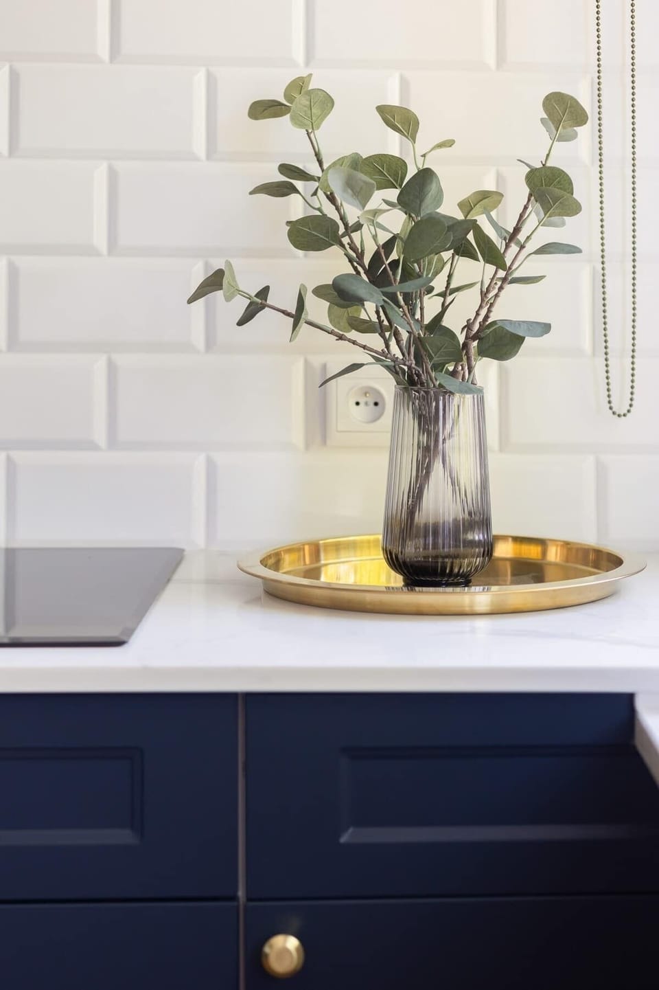 Another kitchen image, showing the white cabinetry, a countertop, and a potted plant. The overall design is neat and functional.