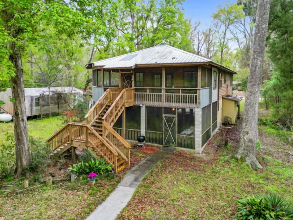 Back view of cabin with screen porches and pathway leading to the river. 