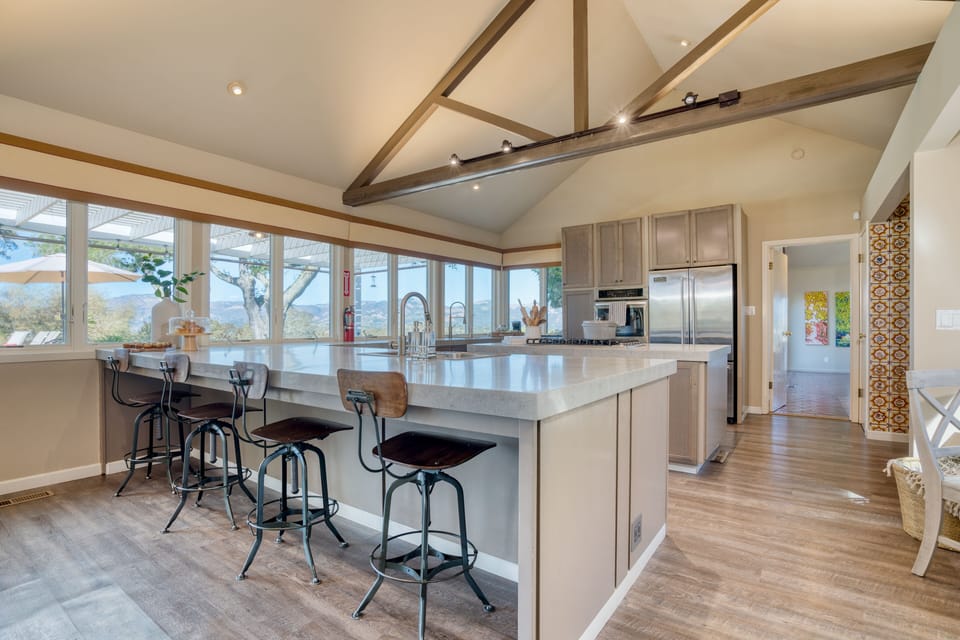 Fully-equipped kitchen with a large island, gas range, barstool seating, and a full suite of appliances.