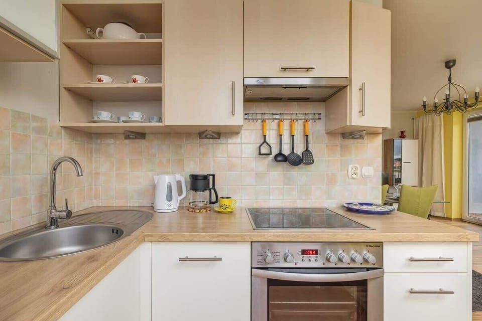 A compact kitchen with white cabinetry, a tiled backsplash, and modern appliances, including an oven and microwave.
