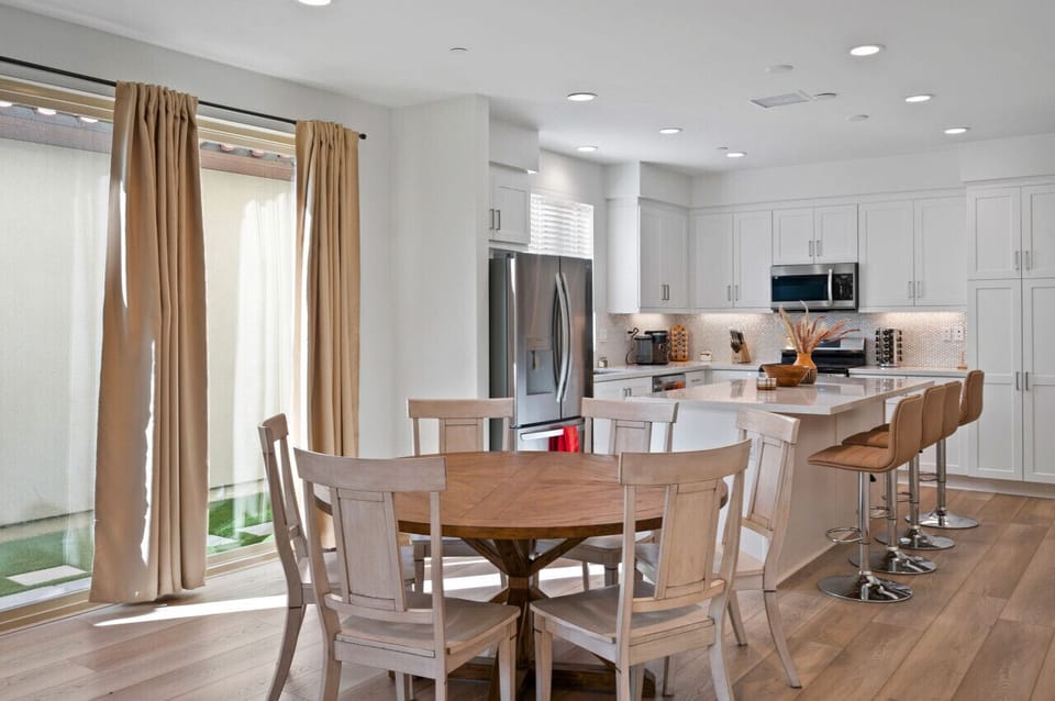 Open kitchen & dining area w/ white cabinetry, wood table & plenty of space to gather