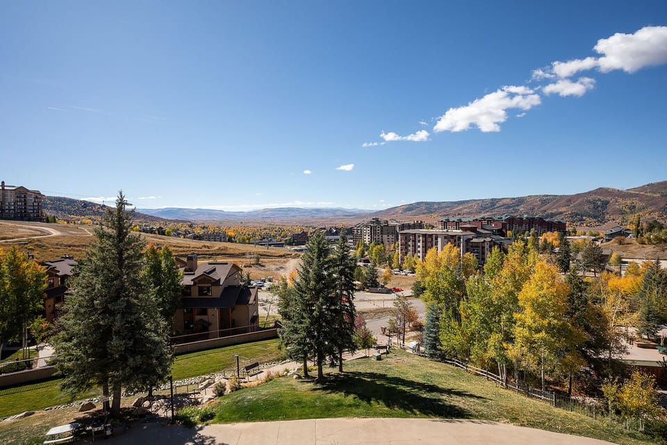 Mountain resort community nestled in a valley with colorful autumn foliage and rolling hills stretching into the distance.