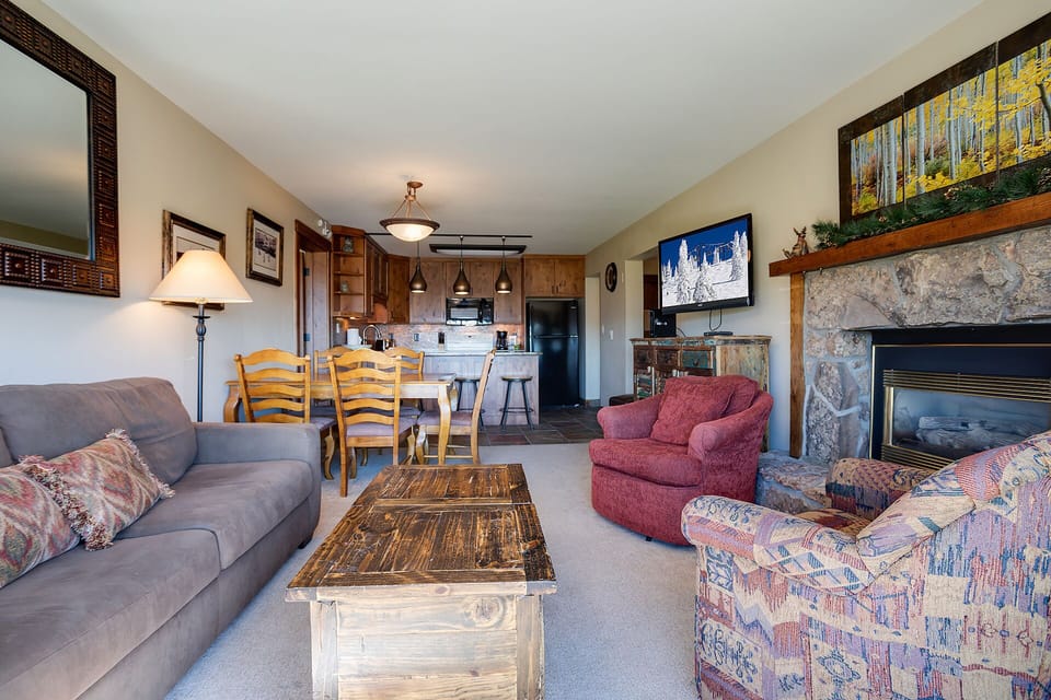 Settle into this cozy living room where you'll find comfortable seating by a stone fireplace, with a full kitchen ready for your mountain getaway.