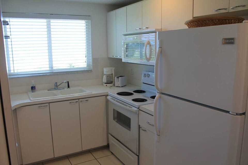 Fully supplied kitchen with dishwasher, stove, microwave, refrigerator, coffee maker, and toaster.