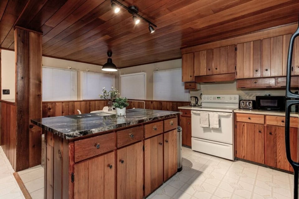 Gather in this charming kitchen where rustic wood cabinetry and a sleek stone island set the scene for delicious meals and great conversation. Whether you are sipping your morning coffee or preparing a feast, this cozy space invites you to slow down and s